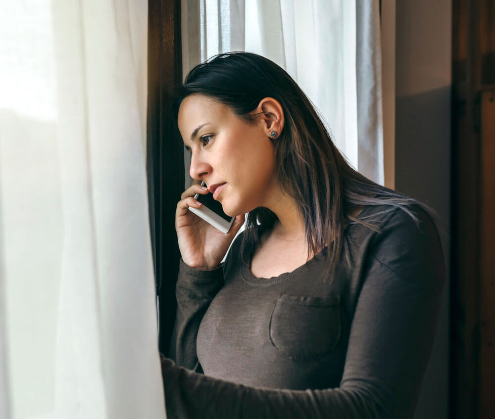 Woman talking on a cellphone while looking out a window.